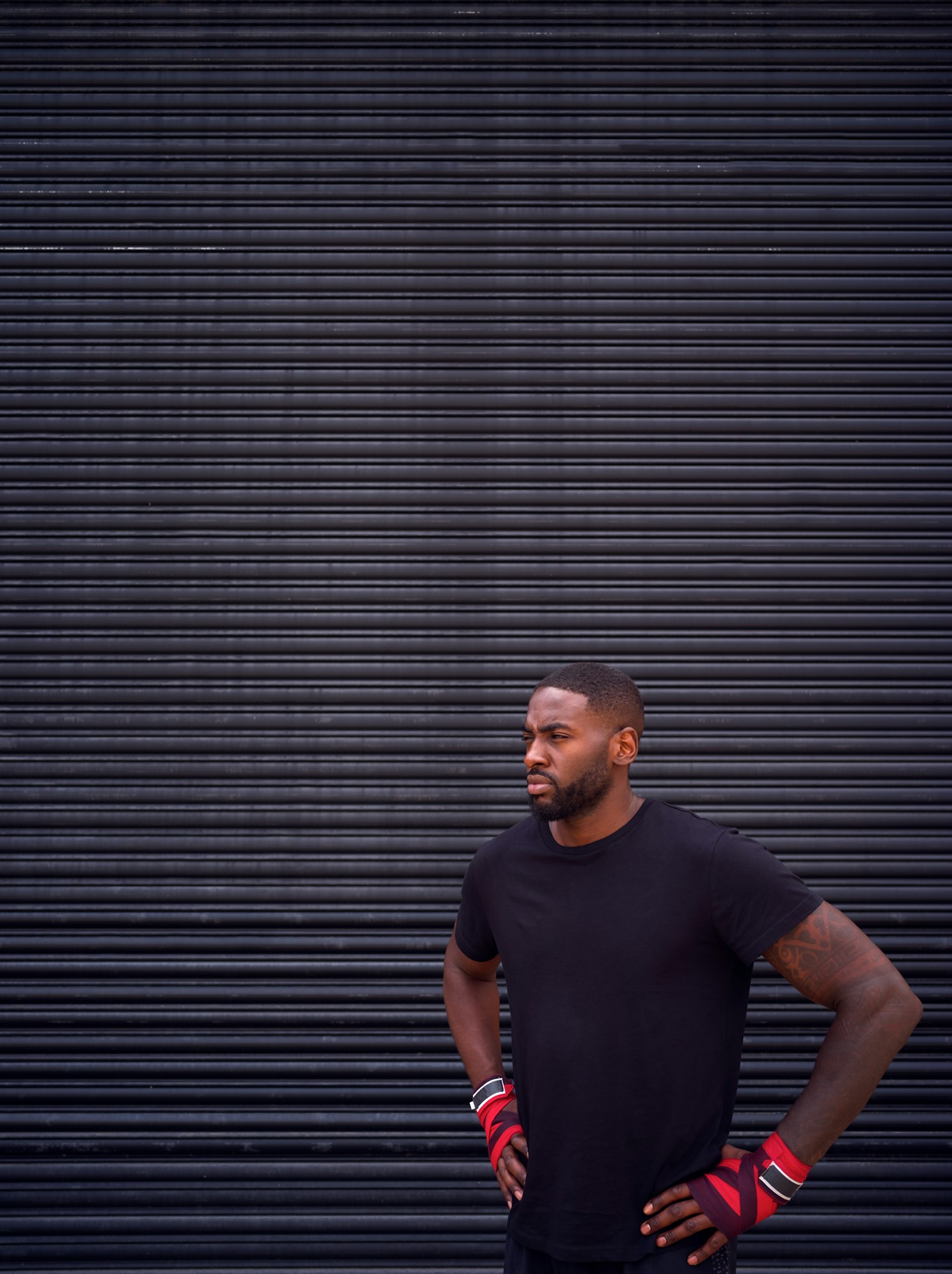 Male Boxer With Wraps On Hands Standing By Metal Shutter Outside Gym